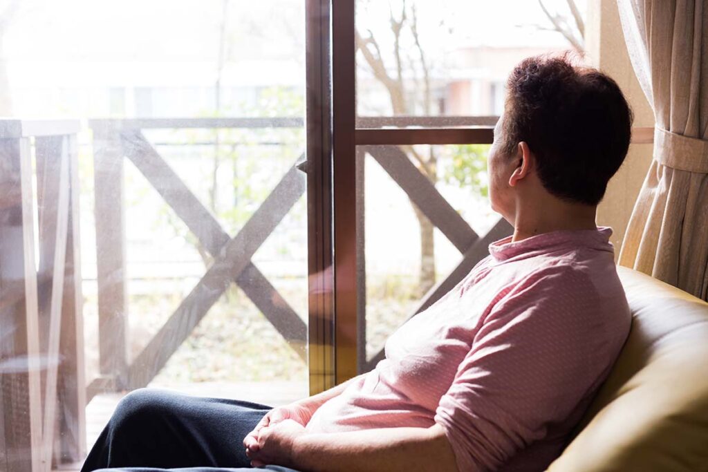 man looking out window wondering about Mental Illness Awareness Week