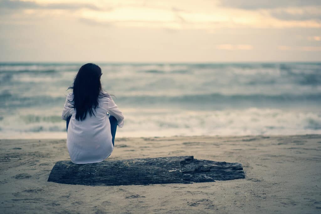 woman sitting o beach coping with disappointment