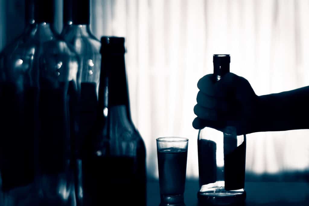 silhouettes of bottles and a hand holding them showing dangers of binge drinking