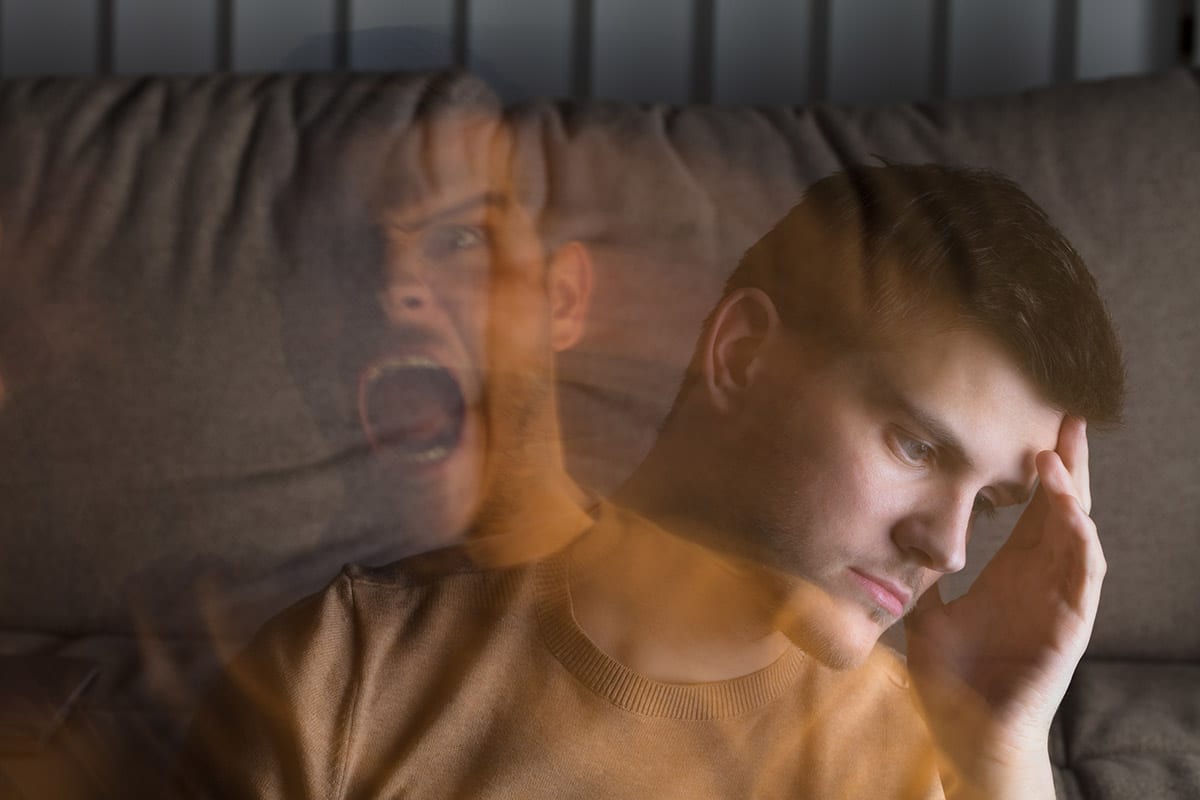 a man presses his fingertips to his forehead as he wonders do i have bipolar disorder