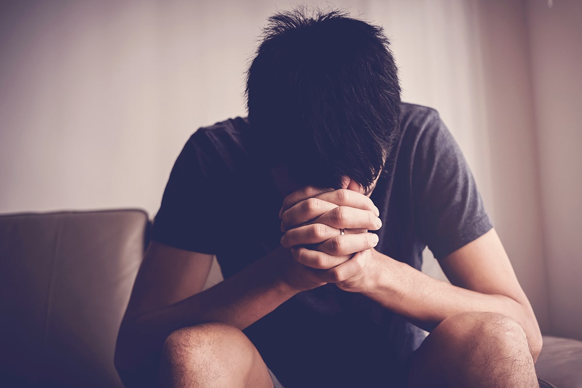 man on couch with head on hands Essential Business Workers