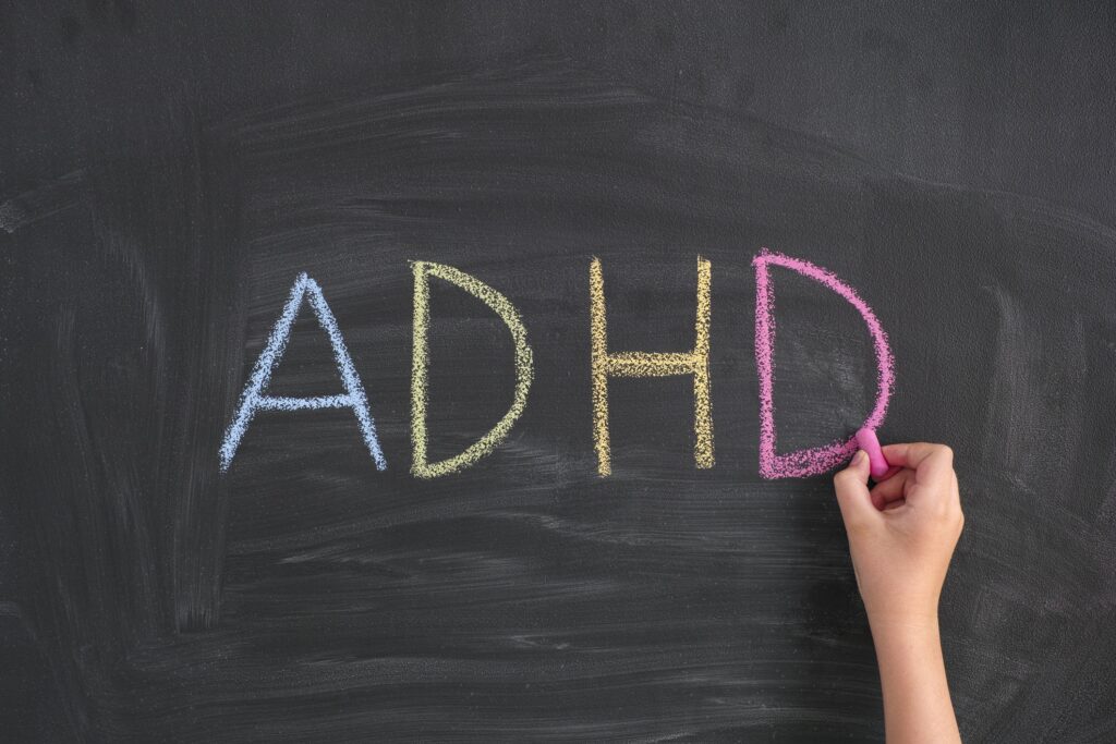 Child writing Abbreviation ADHD on a blackboard