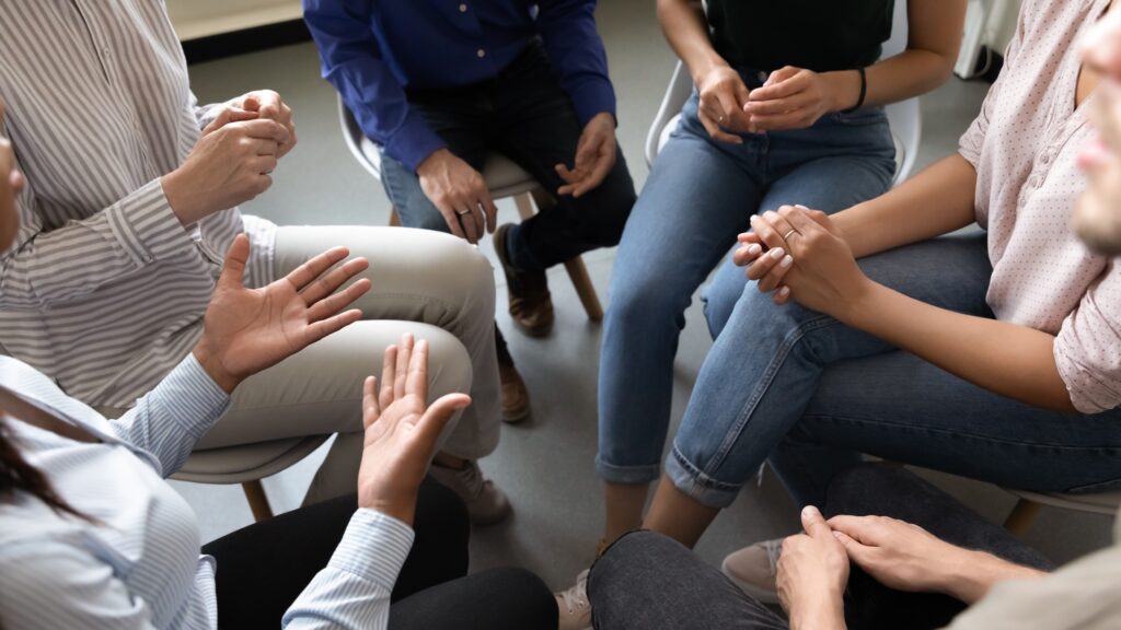 Top close up view of people sitting in a circle doing discussion