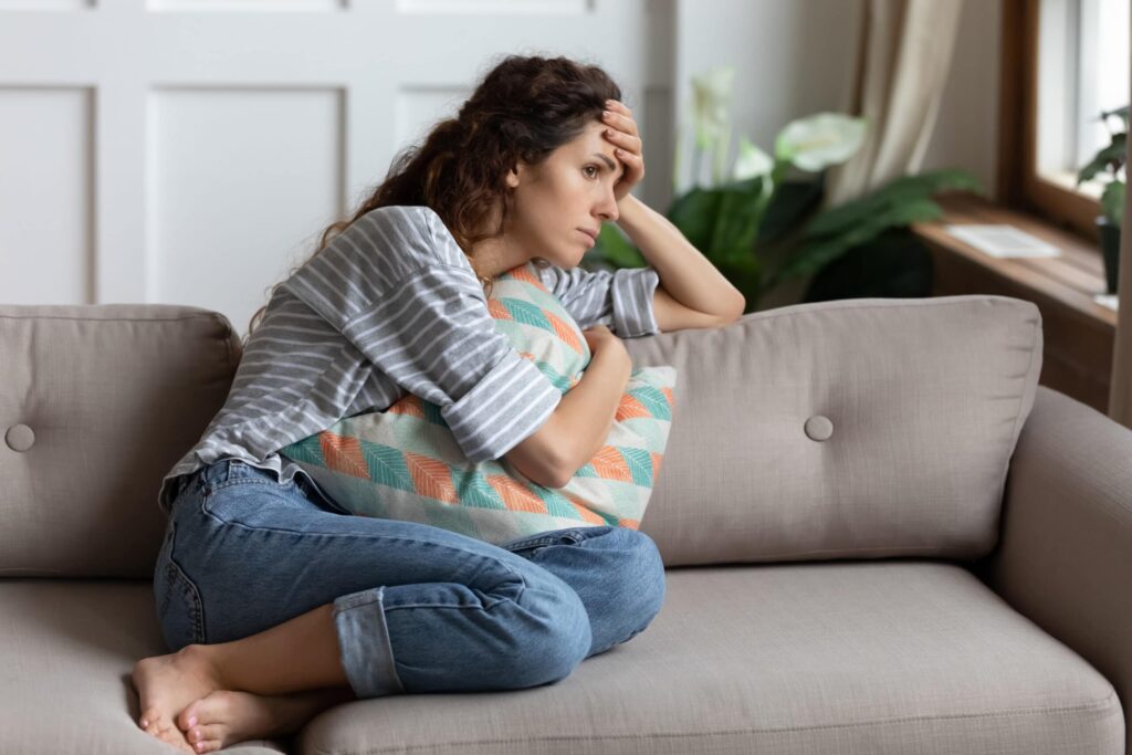 Frustrated young lady sitting on sofa