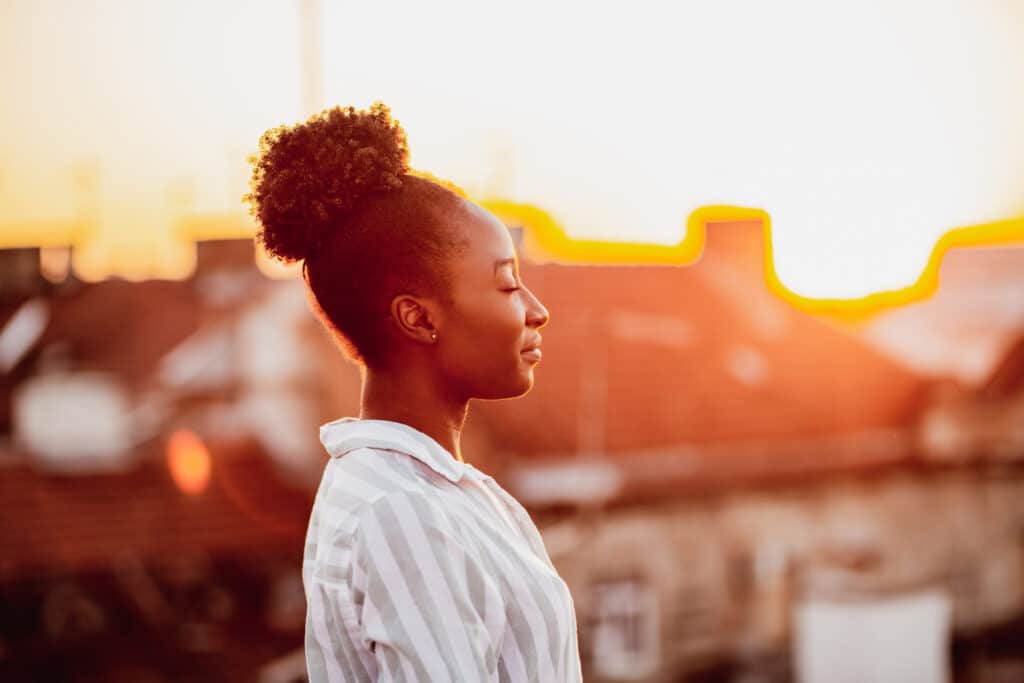 Young African American woman is on the balcony at sunset