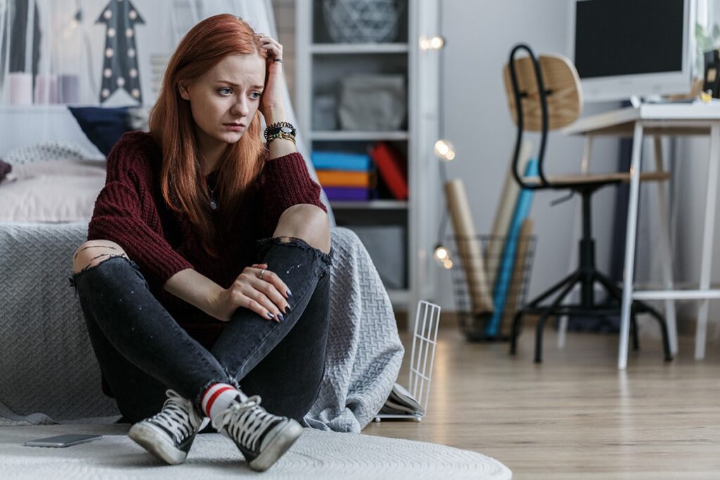 A woman sits on the floor and thinks about the signs of depression