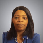 A woman with straight black hair, wearing a blue collared shirt and a gold necklace, looks directly at the camera against a plain light gray background.